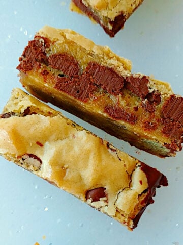 Chocolate chip cookie bars, cut in half. One rests normally to show the shiny top; the other is on its side to show the interior texture.