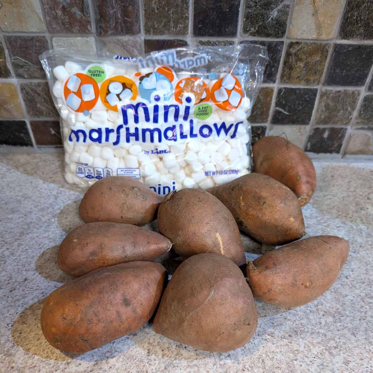 A bag of miniature marshmallows and several raw whole sweet potatoes.