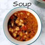 A bowl of Mexican soup on a table, with a side of the cooking pot visible. Text overlay for Pinterest reads "Easy Mexican Soup. Quick + Healthy. Easy As Cookies."