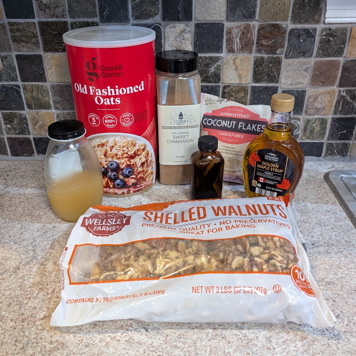 Oats, ground cinnamon, unsweetened coconut flakes, aquafaba in a glass jar, vanilla, maple syrup, and shelled walnuts.