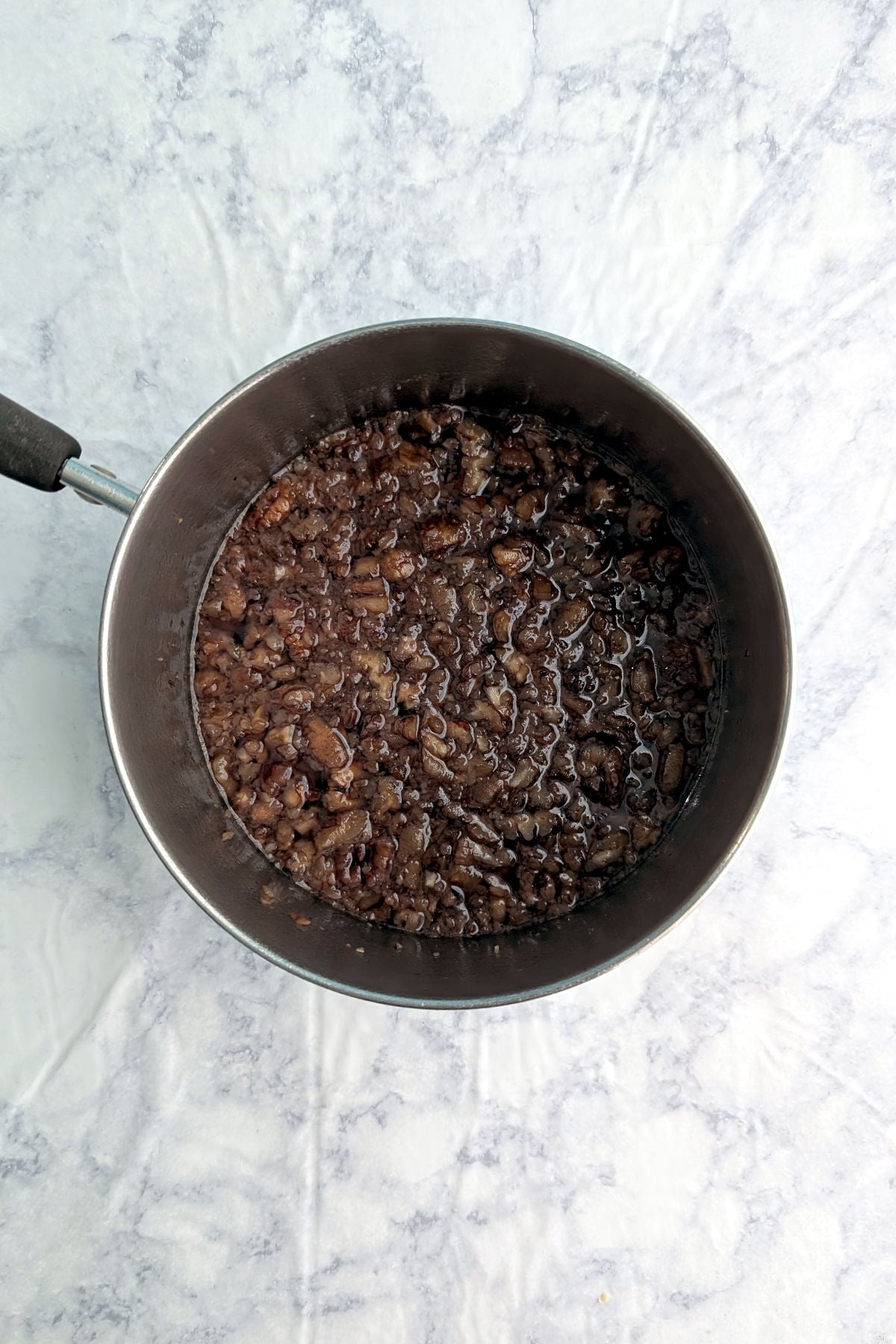 Toasted pecan syrup, after simmering, in a small saucepan.