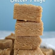 4 squares of peanut butter fudge stacked on top of each other. Text overlay for Pinterest reads "Holiday Peanut Butter Fudge. 6 Ingredients | 30 Minutes. Perfect for Gifting."