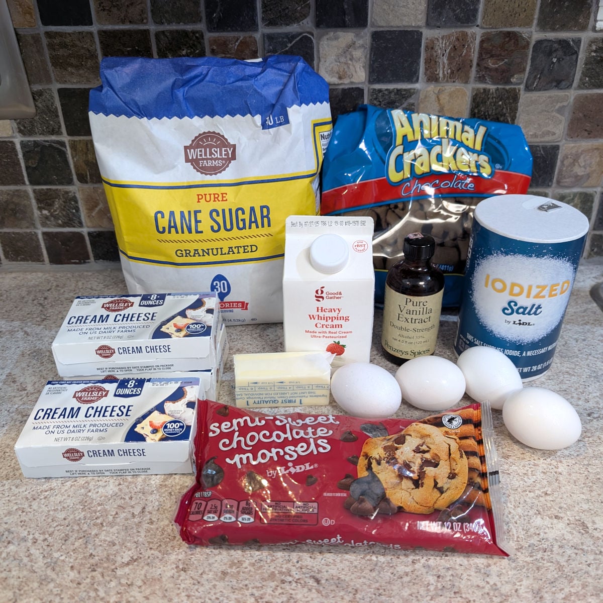 Ingredients for Brownie Cheesecake: sugar, chocolate graham crackers, 3 packages of cream cheese, butter, heavy cream, chocolate chips, eggs, vanilla extract, salt. Not pictured: brownies.