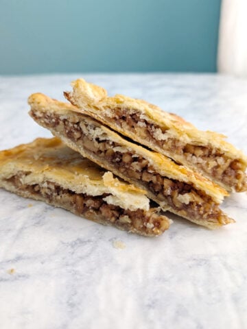 Three slices of Freeform Honey Walnut Pie, layered on each other in a stack. Wedges are seen from the side to see nut filling.