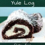 A Flourless Chocolate Yule Log on a tray, dusted with powdered sugar. The cut side facing the camera shows the whipped cream swirl. Text overlay for Pinterest reads "Flourless Chocolate Yule Log. Gluten-Free Christmas Dessert. Easy As Cookies."