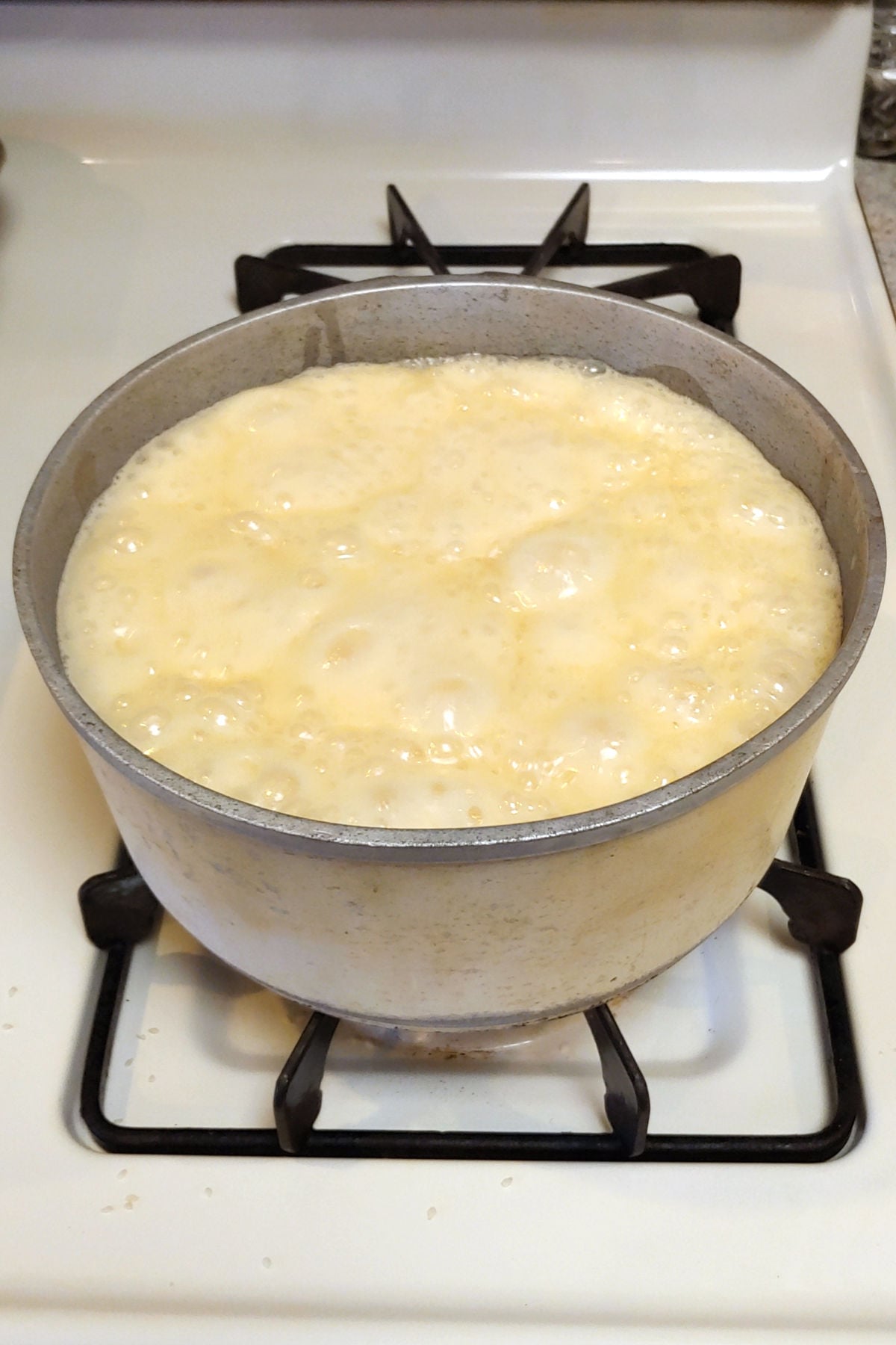Milk-syrup mixture at a rolling boil in a pot on the stove.