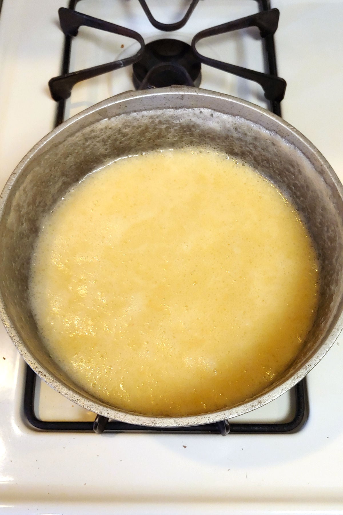 Milk syrup in a pot on the stove, having deflated when heat is turned off.