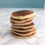 A stack of seven pancakes on a table. The top one is made with all-purpose flour; the bottom six are made with half all-purpose and half whole wheat flour.
