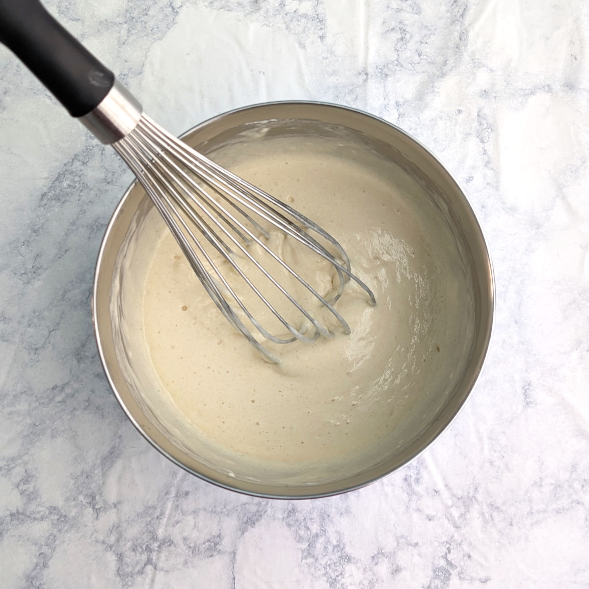 Everyday pancake batter, mixed together, in a bowl with a wire whisk.