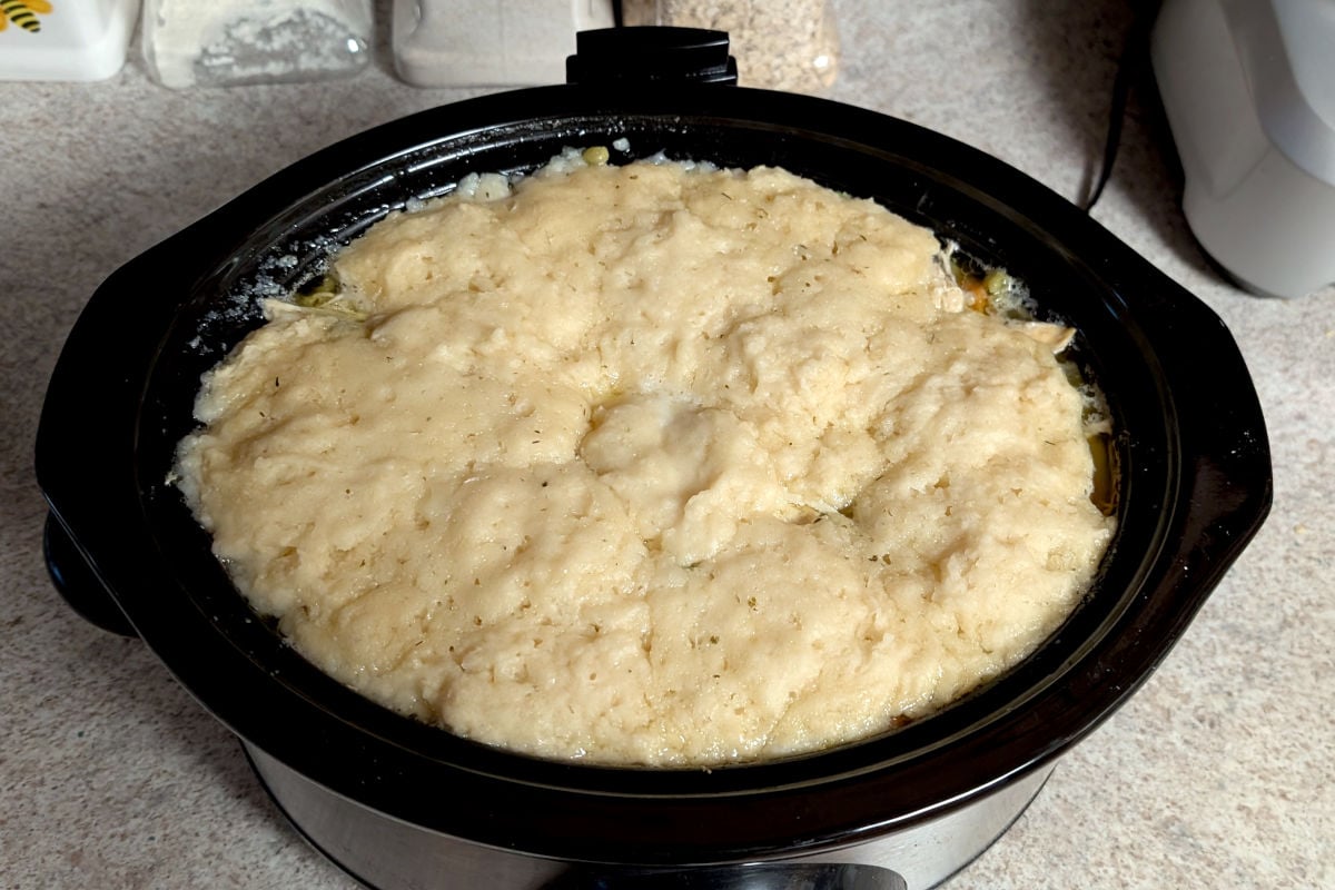 Cooked dumplings on top of chicken soup in a 6 quart slow cooker. Dumplings stay below the top of the crock.