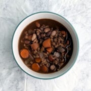 A bowl of slow cooker southwestern bean and barley soup, with beans and carrots visible on the top.