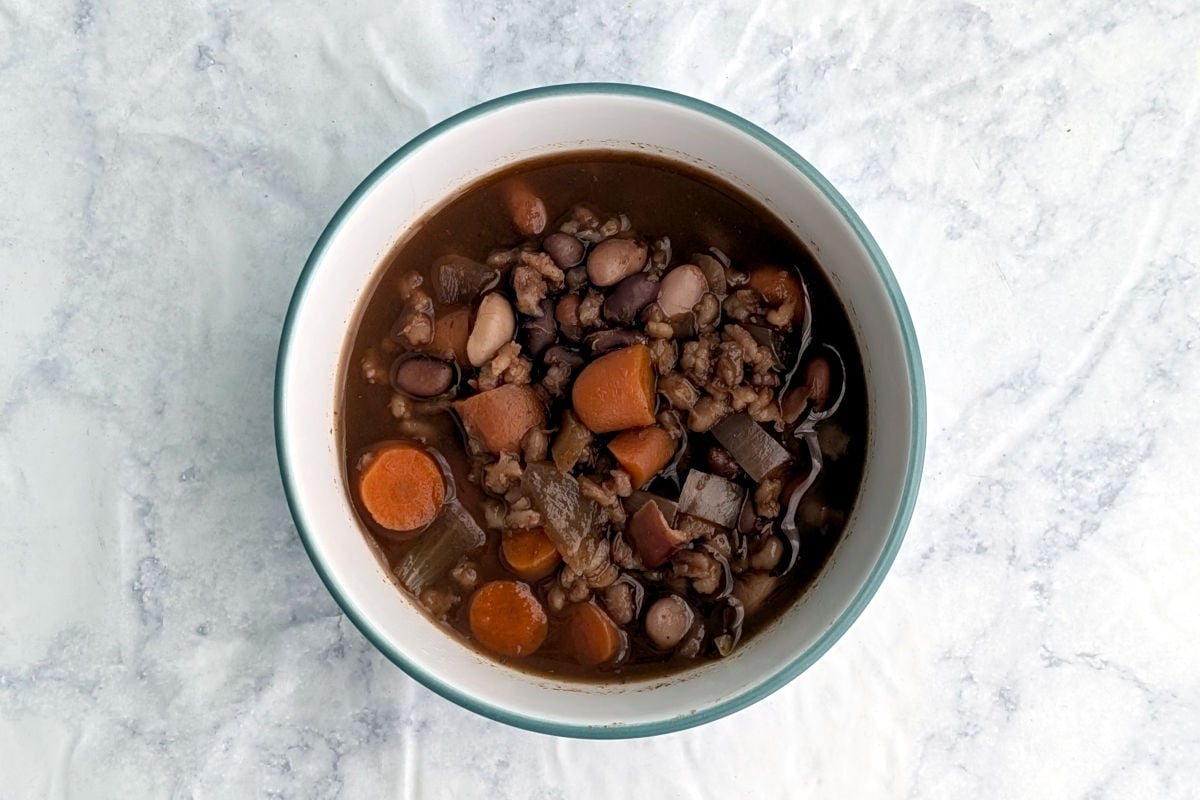 A bowl of slow cooker southwestern bean and barley soup, with beans and carrots visible on the top.