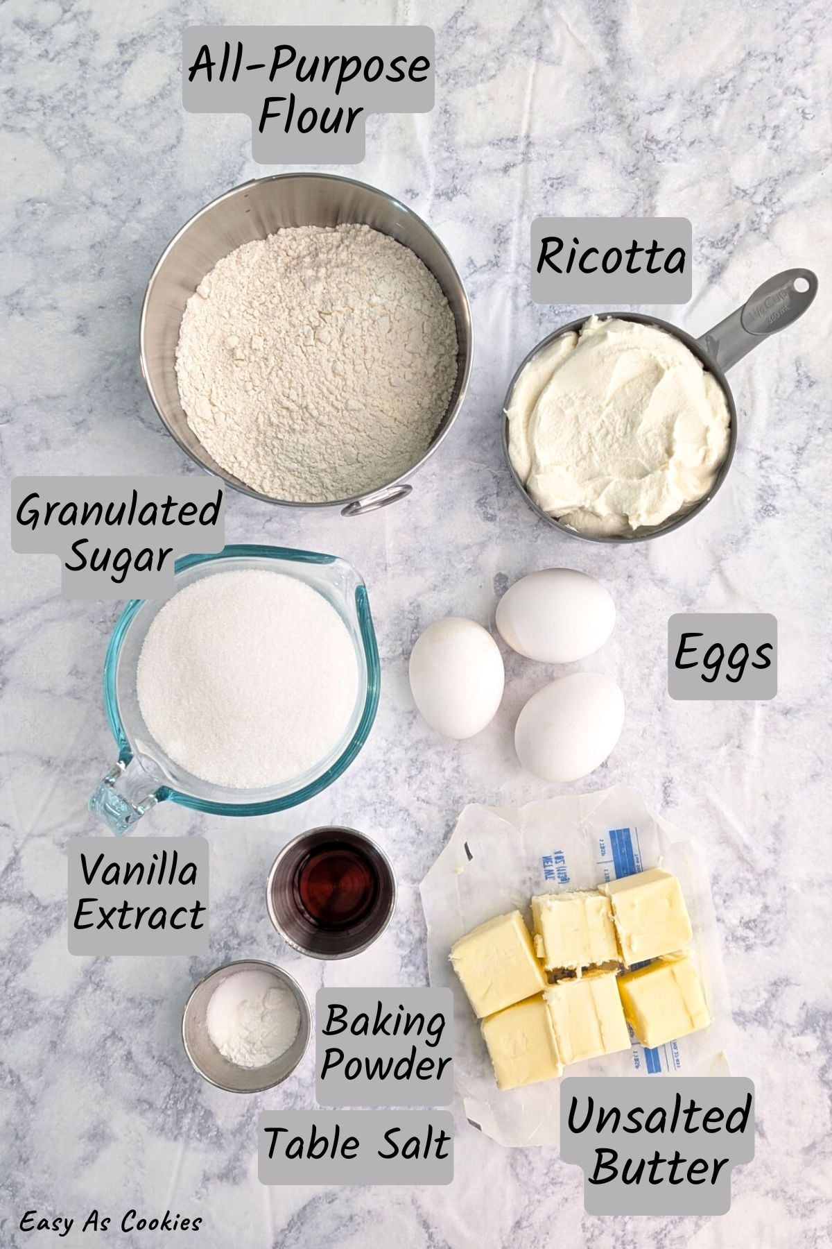 A labeled photo with ingredients for ricotta pound cake, including: all-purpose flour, granulated sugar, ricotta cheese, 3 eggs, vanilla extract, unsalted butter, baking powder, and table salt. Branding at the bottom reads "Easy As Cookies."