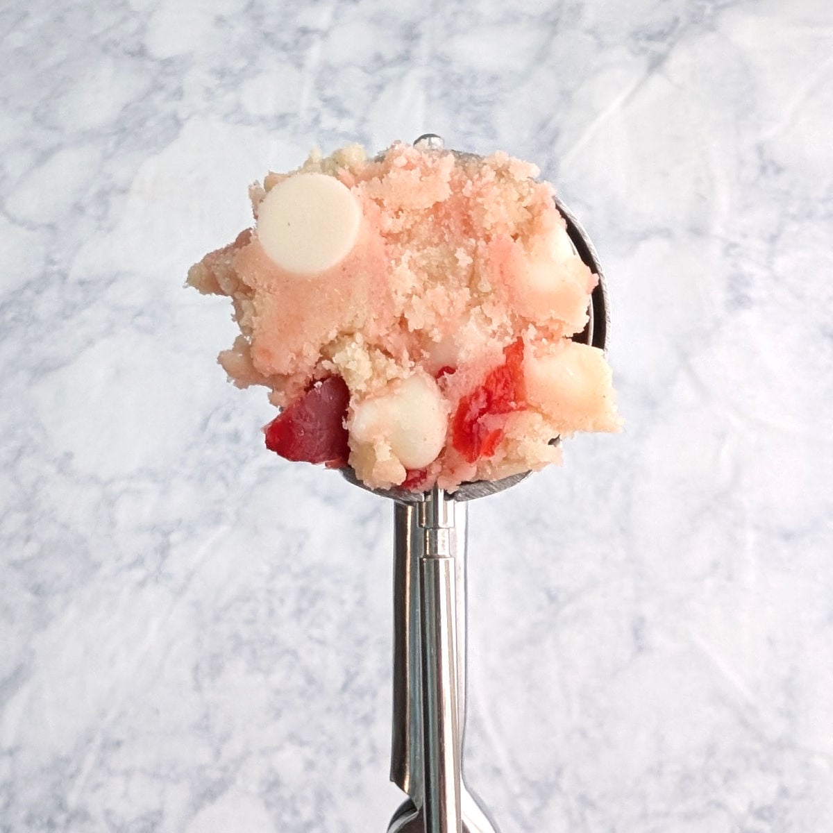 White chocolate cherry shortbread cookie dough, in a small cookie scoop.