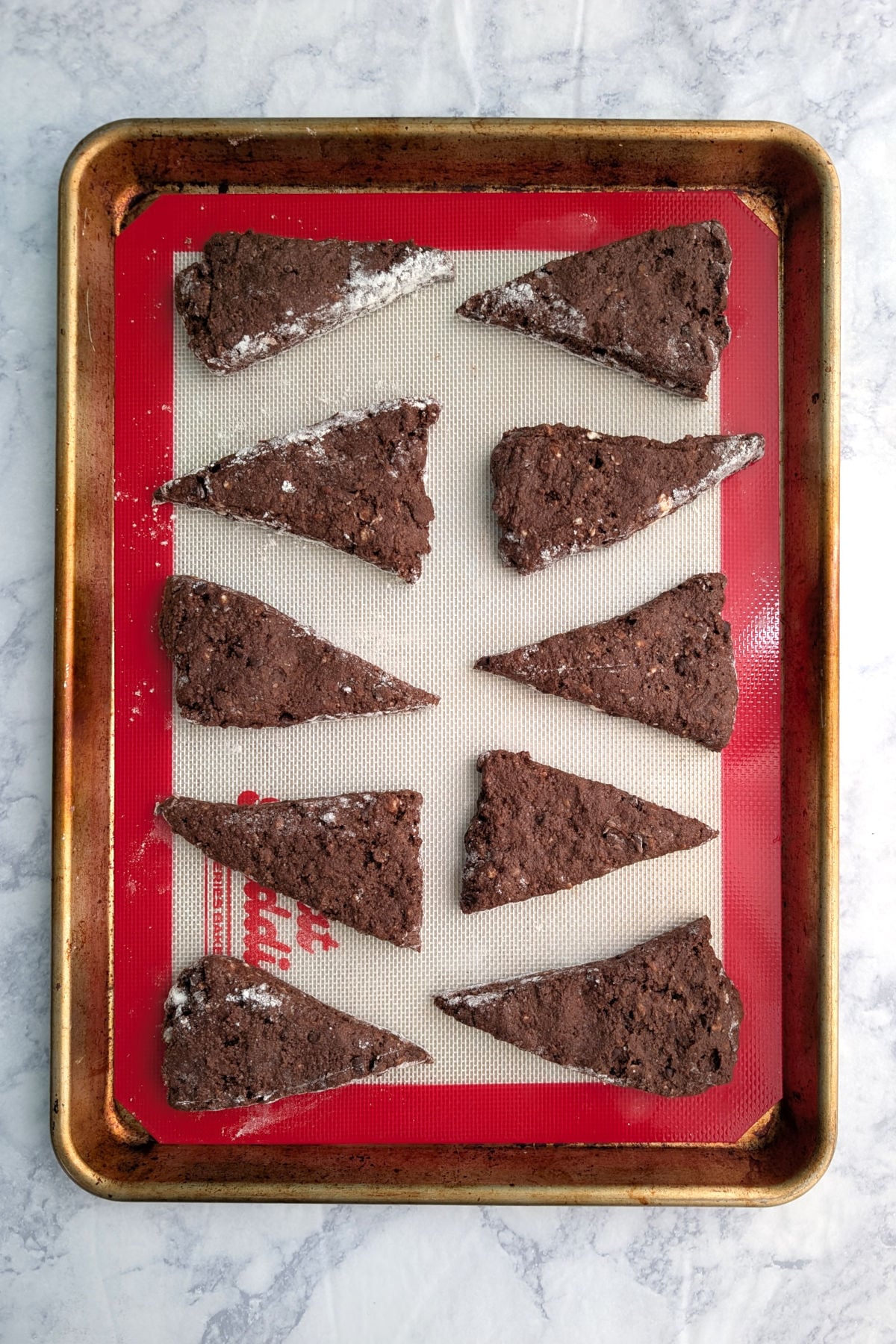 Double chocolate scone wedges, on a silicone mat lined baking sheet, before baking.
