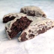 Glazed double chocolate scones on a table. One scone is broken open to show texture.