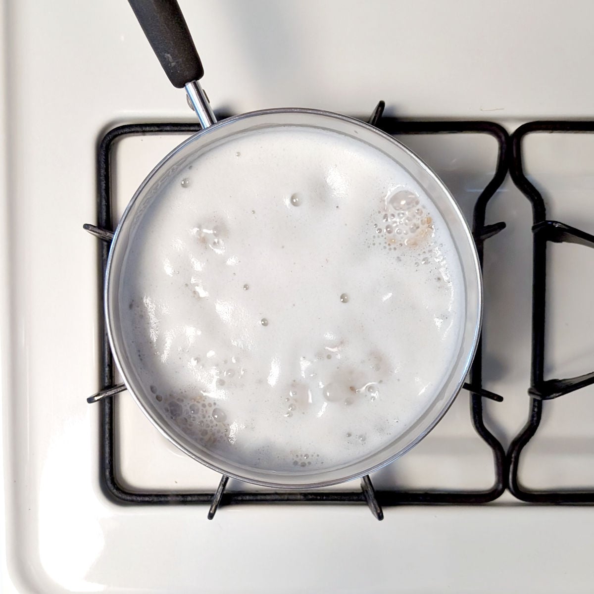 A pot with milk and steel cut oats that has just come to a boil.