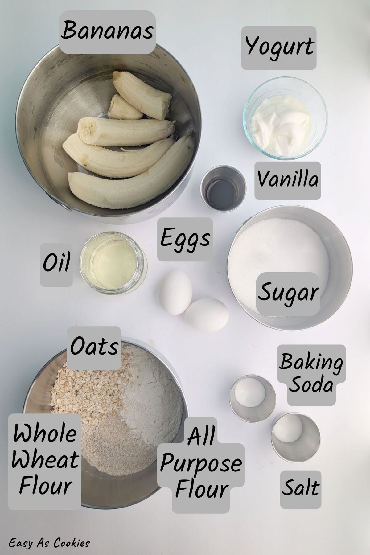 Labeled photo of ingredients for Classic Banana Bread with Oats, including bananas, yogurt, oil, vanilla, eggs, sugar, baking soda, salt, oats, whole wheat flour, and all purpose flour.