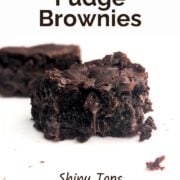 A fudge brownie missing a bite, with chocolate dripping from the center. Text overlay reads "One-Bowl Fudge Brownies. Shiny Tops. Loaded with Chocolate Chips. Easy As Cookies."
