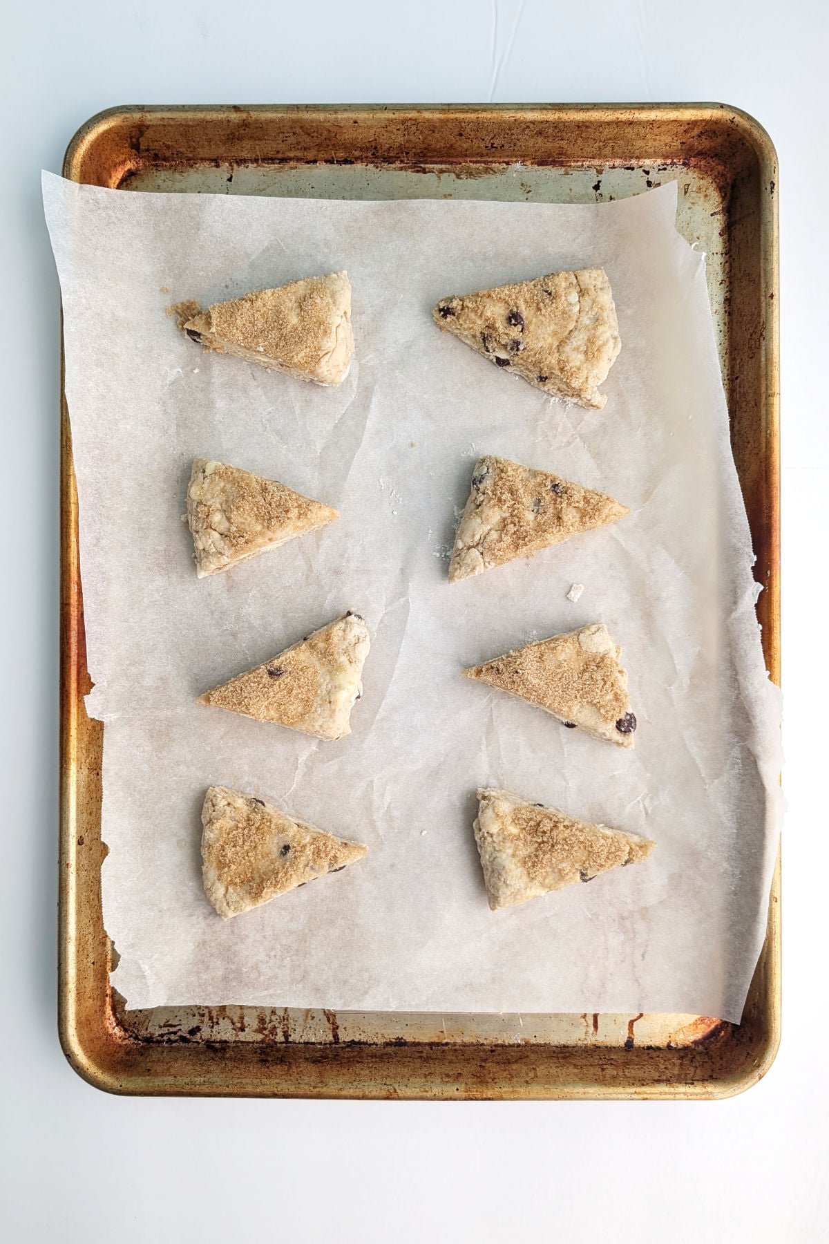 Unbaked chocolate chip cookie scone wedges on a baking sheet.