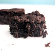 A fudge brownie missing a bite, with chocolate dripping from the center.