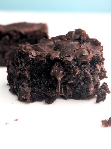 A fudge brownie missing a bite, with chocolate dripping from the center.