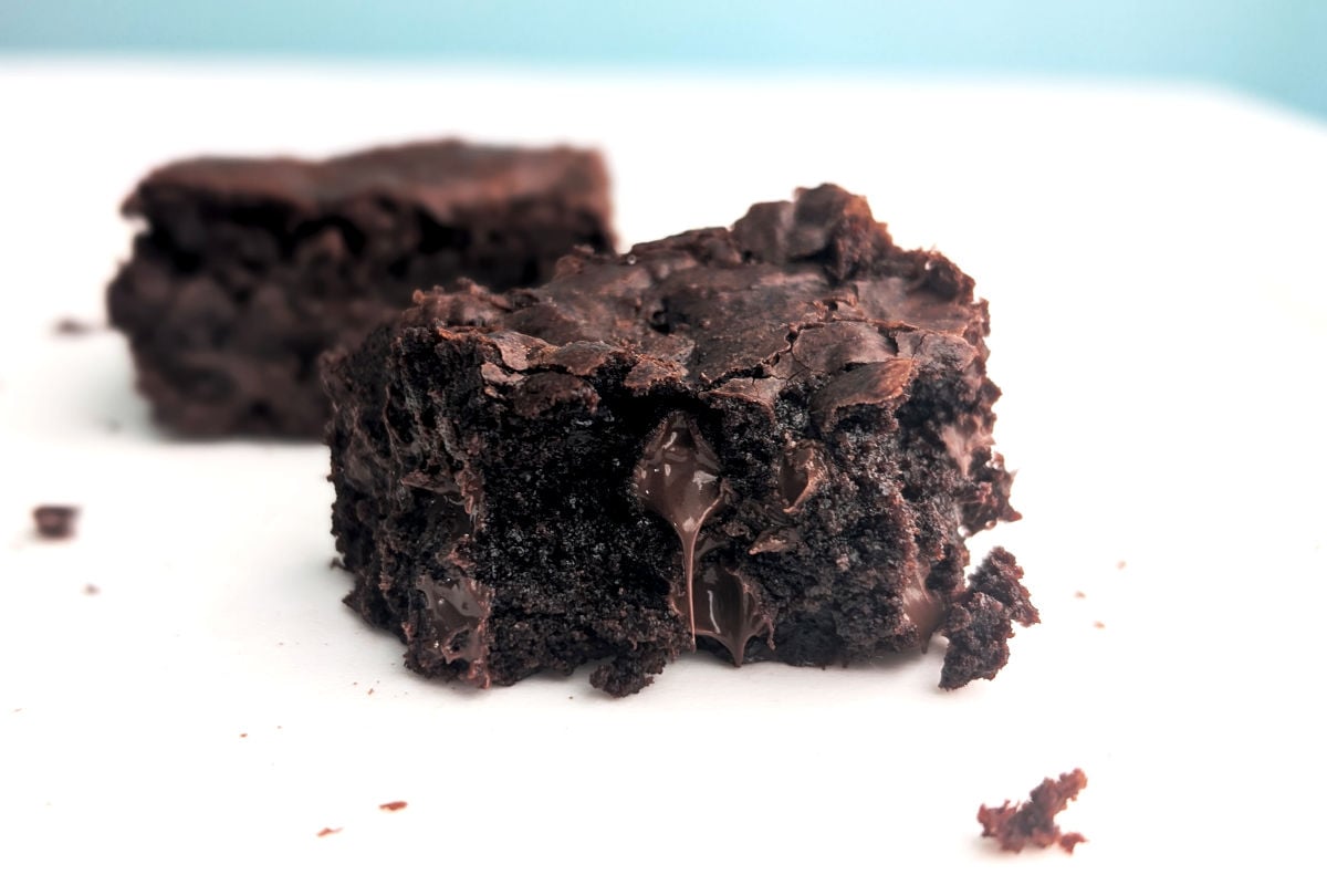 A fudge brownie missing a bite, with chocolate dripping from the center.
