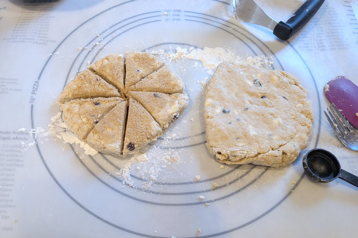 Rounds of dough for chocolate chip cookie scones, patted out. One round is topped with brown sugar and cut into wedges.