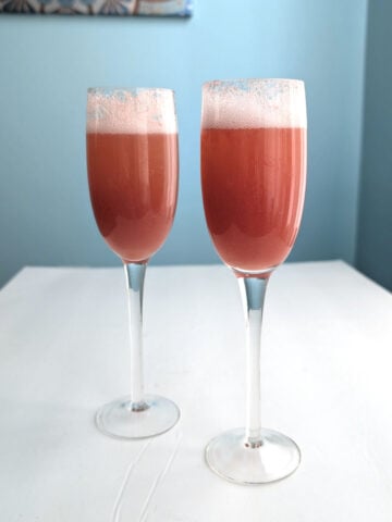 Two strawberry bellinis in champagne flutes.