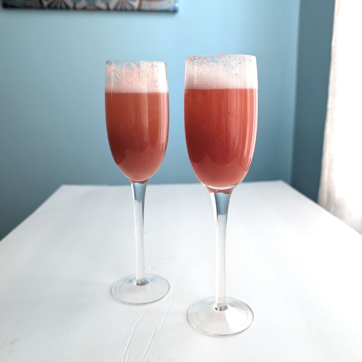 Two strawberry bellinis in champagne flutes.