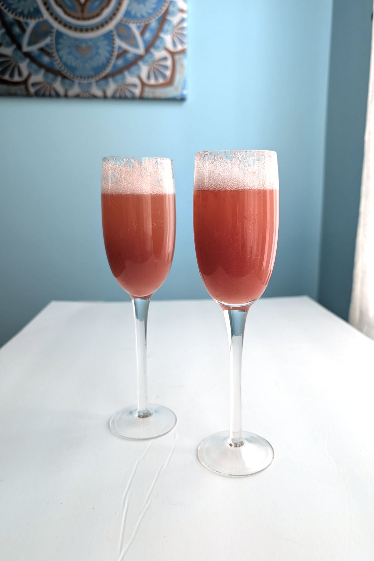 Two strawberry bellinis in champagne flutes.