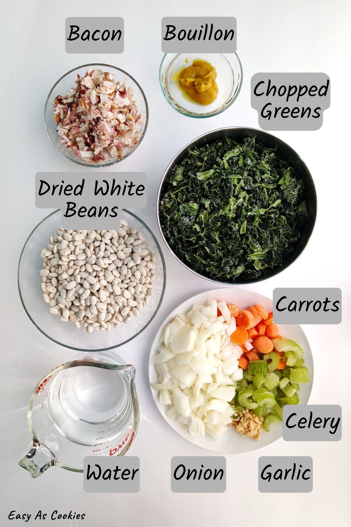 Ingredients for bean and bacon soup, including: bacon, bouillon, dried white beans, chopped greens, water, onion, carrots, celery, and garlic.
