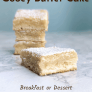 A slice of gooey butter cake, in front of a stack of slices. Text overlay reads "St. Louis Gooey Butter Cake. Breakfast or Dessert. From Scratch. Easy As Cookies."