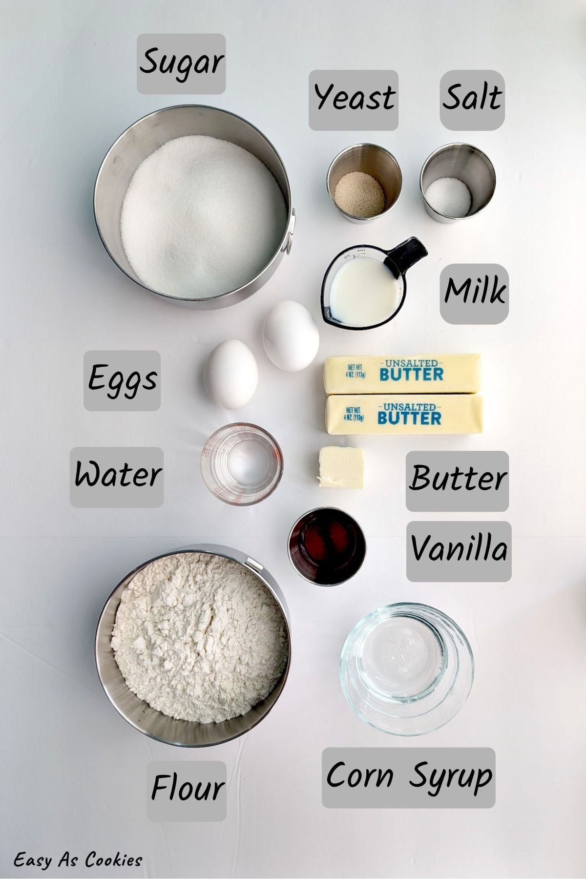 Labeled photo of ingredients for Gooey Butter Cake, including granulated sugar, dry yeast, table salt, eggs, water, milk, unsalted butter, all-purpose flour, vanilla extract, and light corn syrup.