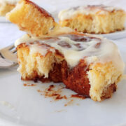Overnight cinnamon roll torn apart to show the swirl of brown sugar cinnamon. A fork holds a bite next to it.