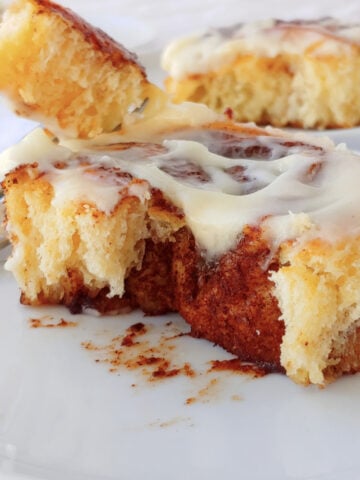 Overnight cinnamon roll torn apart to show the swirl of brown sugar cinnamon. A fork holds a bite next to it.