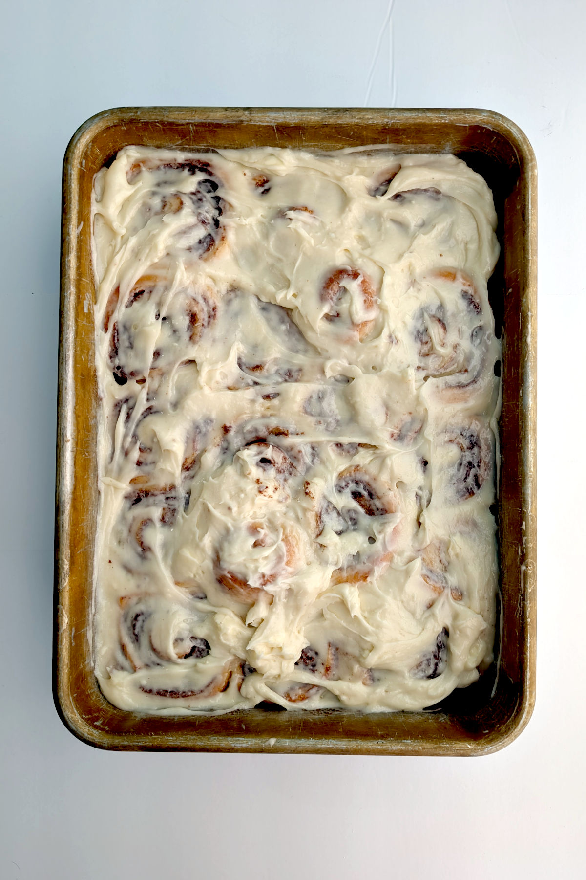 Cinnamon rolls frosted with cream cheese icing in a 9x13 inch pan.