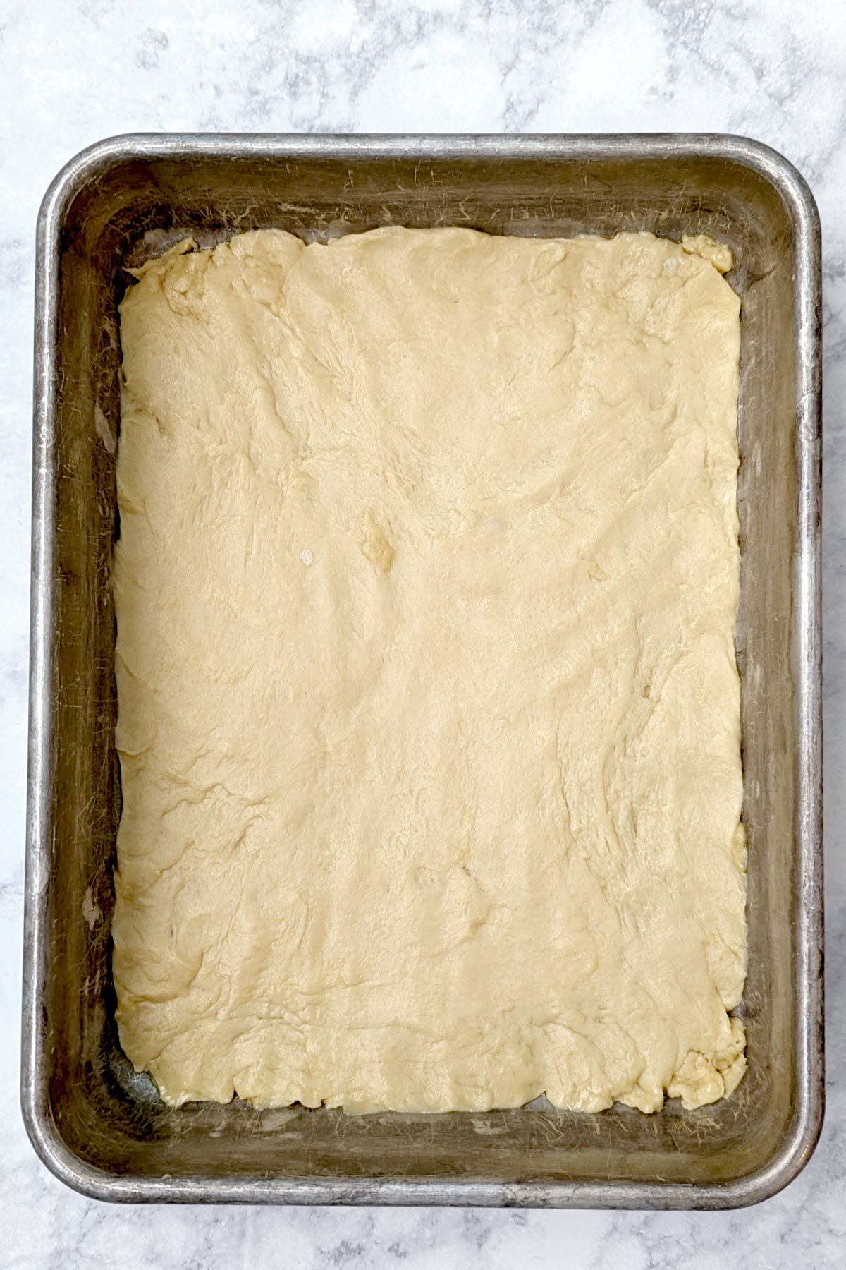 Yeasted cake base for gooey butter cake, patted into the baking dish, before rising.