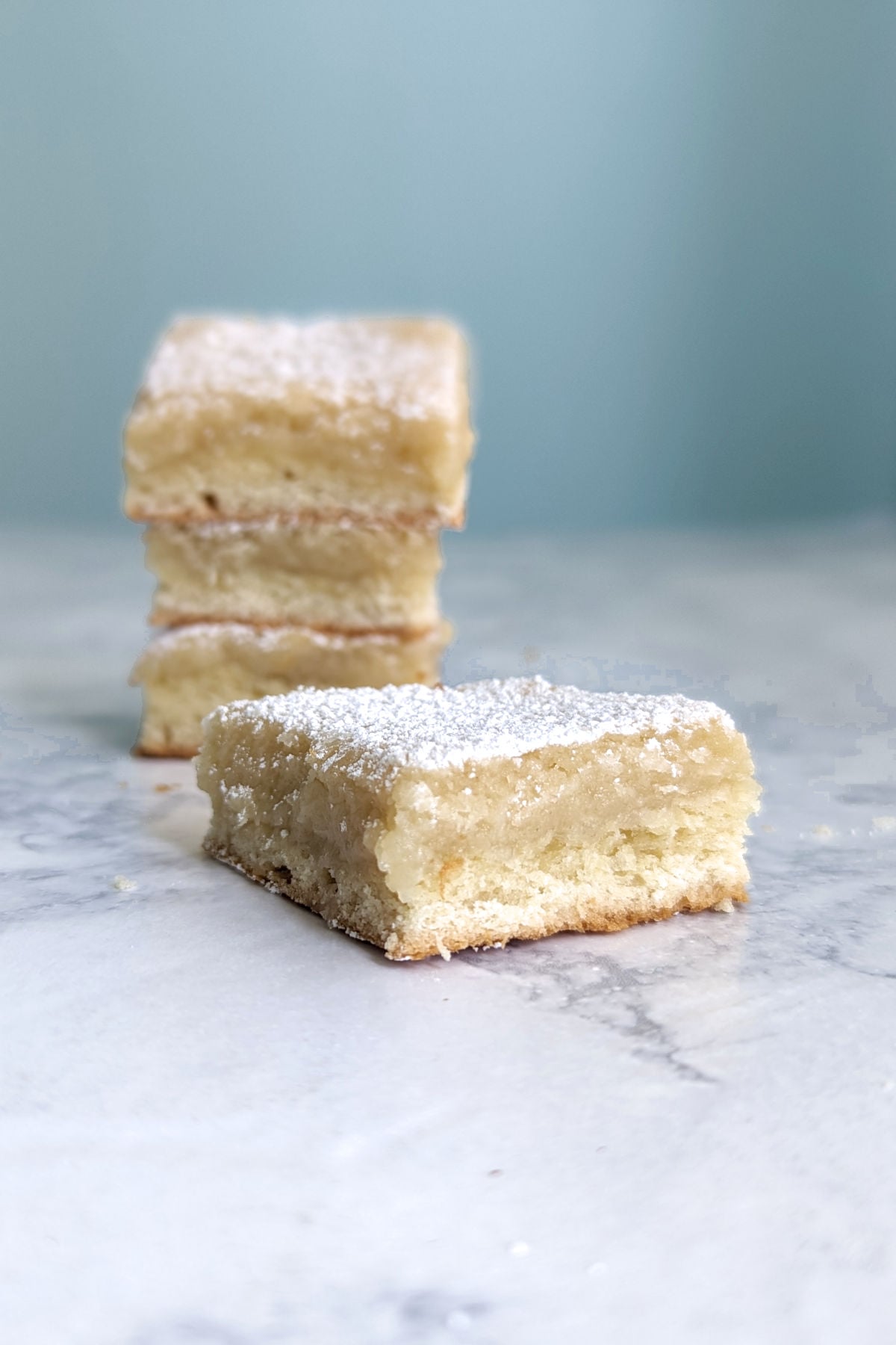 Slice of St. Louis Gooey Butter Cake, in front of a stack of slices.