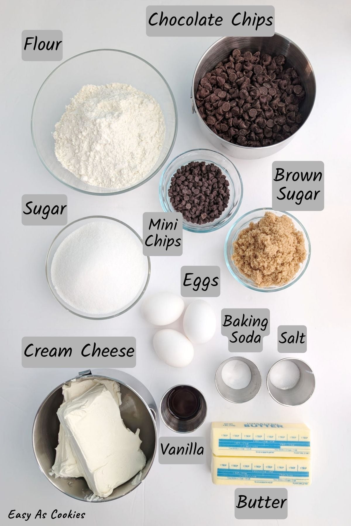 Ingredients for chocolate chip cookie cheesecake bars, including flour, sugar, chocolate chips, miniature chocolate chips, brown sugar, eggs, vanilla, baking soda, salt, cream cheese, and butter.