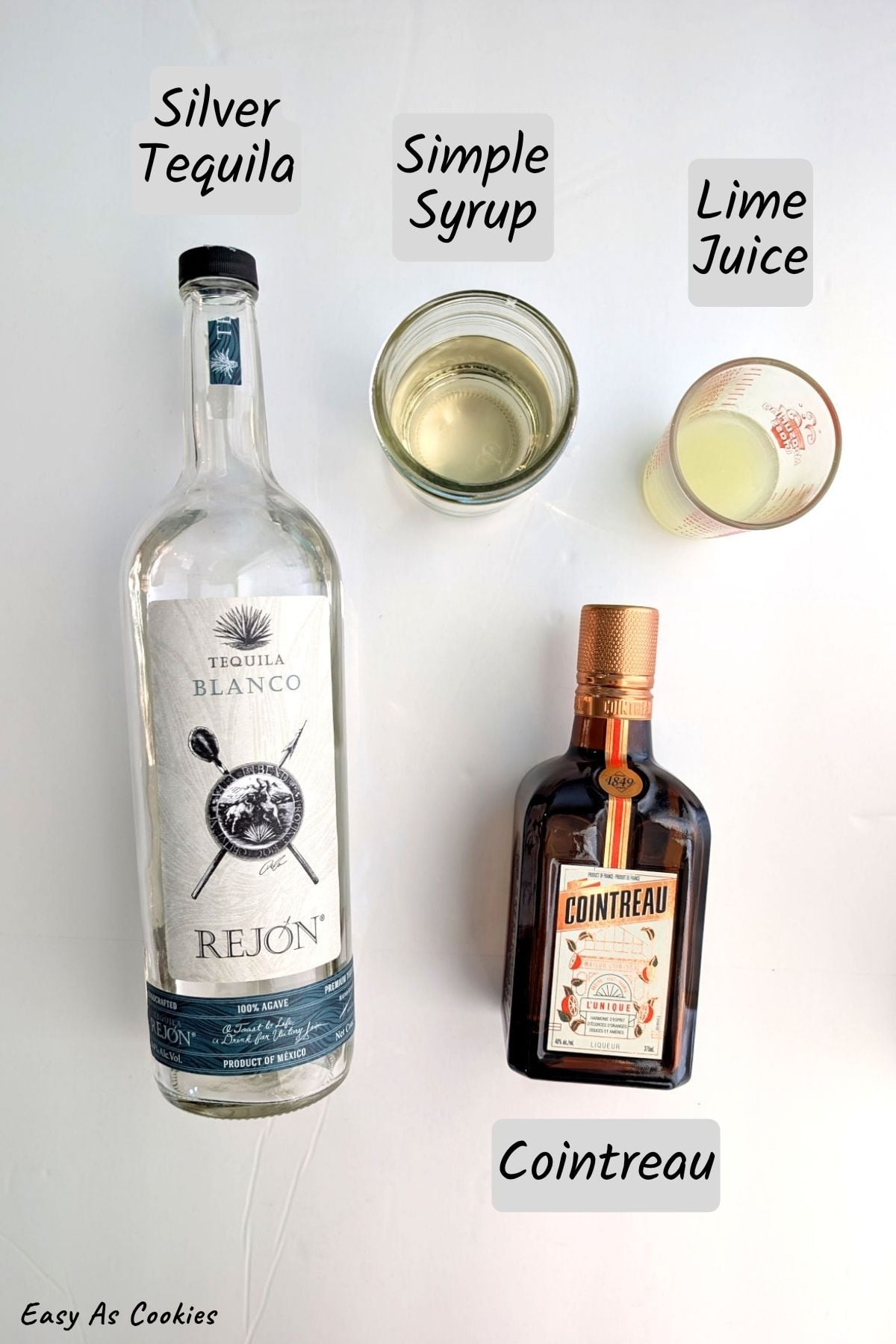 Labeled photo of ingredients for classic margaritas, including tequila, simple syrup, lime juice, and Cointreau.