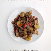 Roast beef hash with potatoes and red bell peppers on a plate. Text overlay reads "Roast Beef Hash. Easy Skillet Dinner. Gluten-Free. Easy As Cookies."