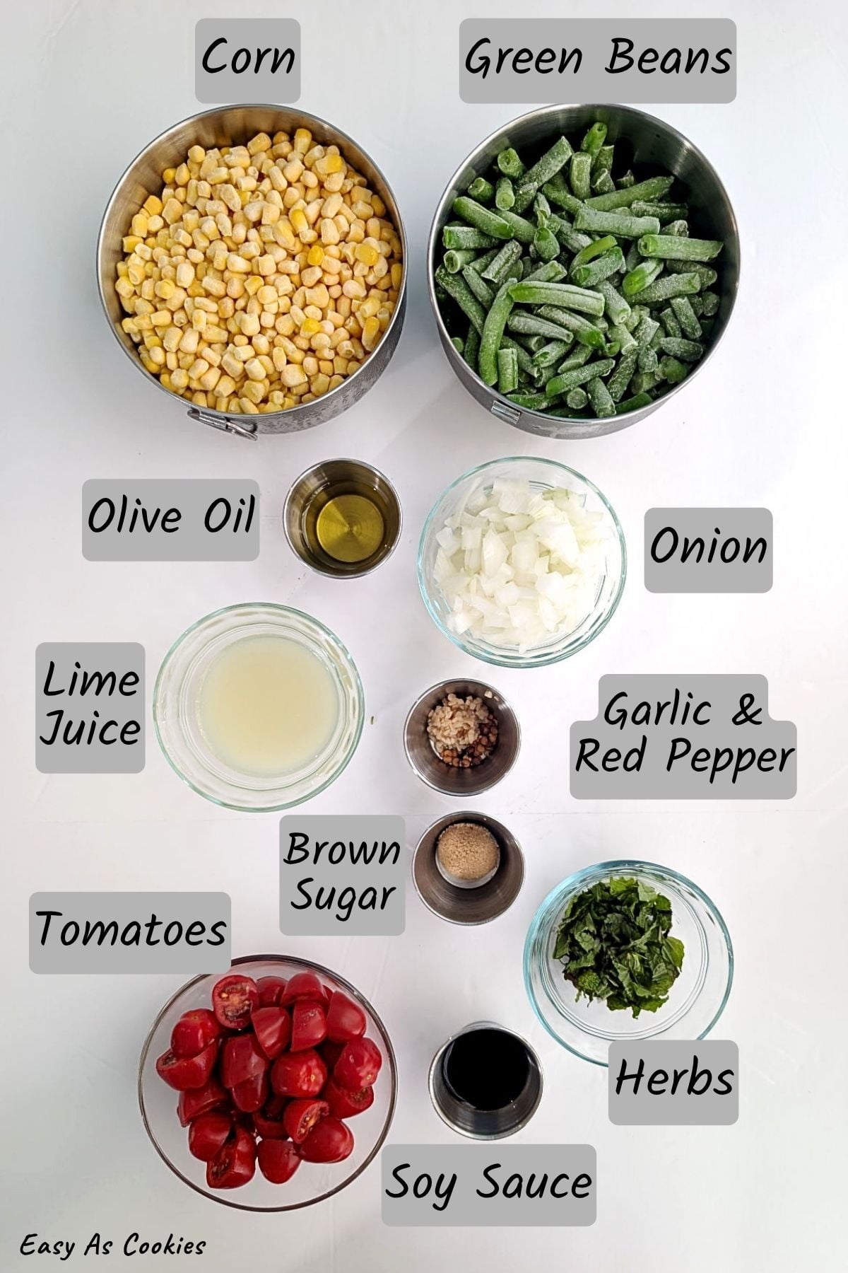 Ingredients for Warm Corn and Green Beans with Lime, including frozen corn, frozen green beans, olive oil, lime juice, onion, minced garlic, red pepper flakes, brown sugar, tomatoes, soy sauce, and fresh herbs.