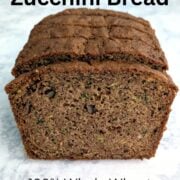 A loaf of whole wheat zucchini bread, sliced and upright, to show texture. Text overlay reads "Whole Wheat Zucchini Bread. 100% Whole Wheat. Stays Moist. Easy As Cookies."