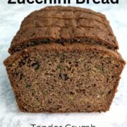 A loaf of whole wheat zucchini bread, sliced and upright, to show texture. Text overlay reads "Whole Wheat Zucchini Bread. Tender Crumb. No Dry Bites. Easy As Cookies."