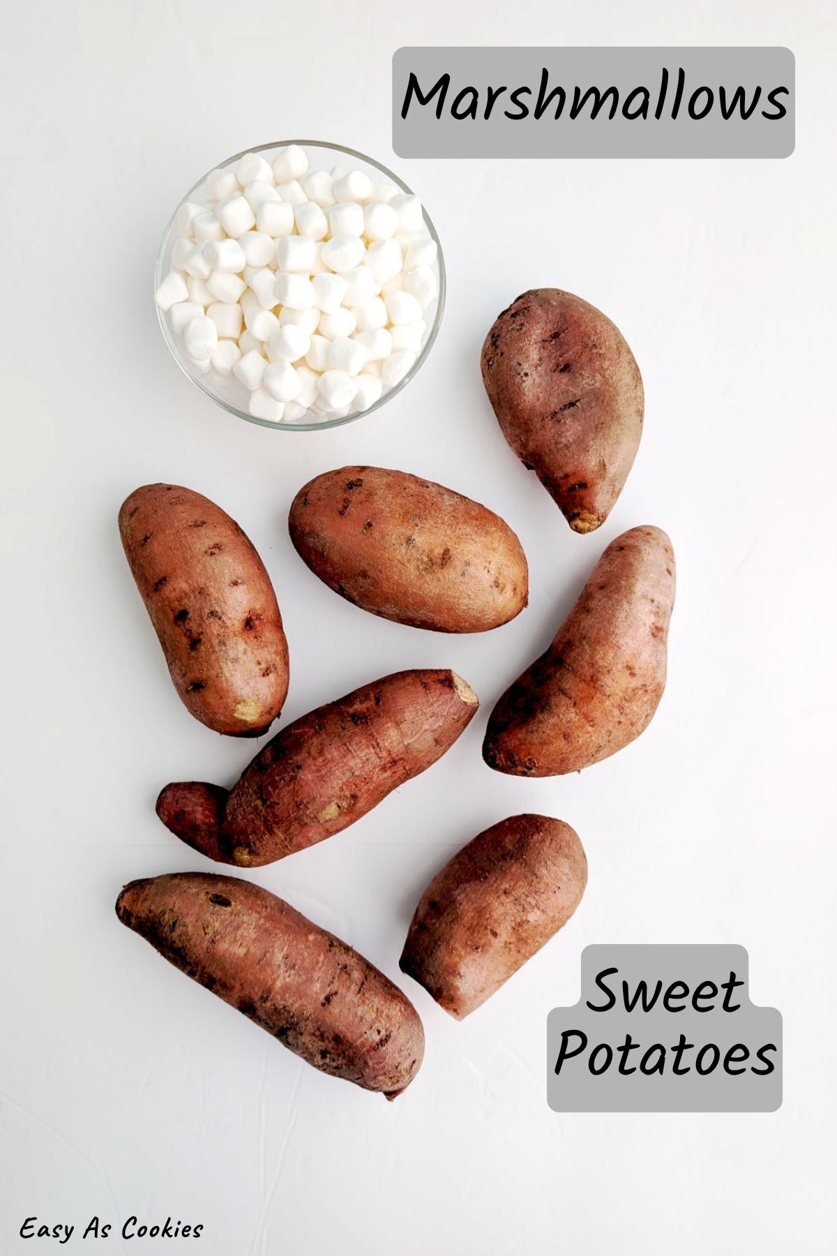Labeled photo with ingredients for Roasted Sweet Potatoes with Marshmallows, including miniature marshmallows and whole uncooked sweet potatoes.