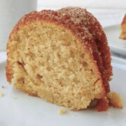 A slice of apple cider donut cake topped with cinnamon sugar.