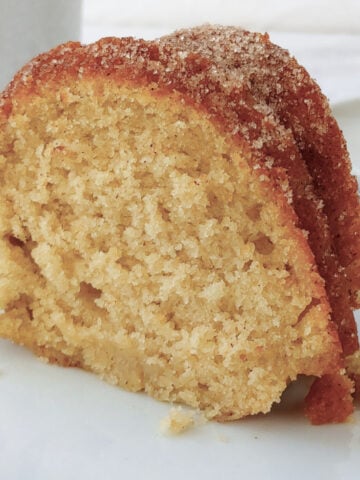 A slice of apple cider donut cake topped with cinnamon sugar.