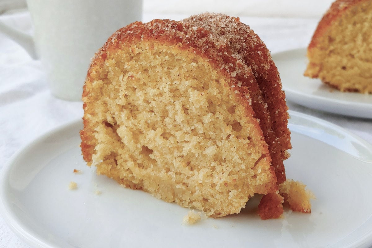 A slice of apple cider donut cake, topped with cinnamon sugar.