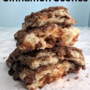 Two layered cinnamon scones, broken in half and stacked to show texture. Text overlay reads "Layered Cinnamon Scones. Cinnamon Roll Flavor. Easy As Cookies."